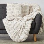 
                    
                      Manta blanca texturizada draped sobre sillón gris con patas madera-
                    
                  