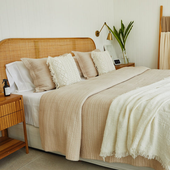 Cama con cubrecama beige tradicional, almohadas decorativas y plantas-beige