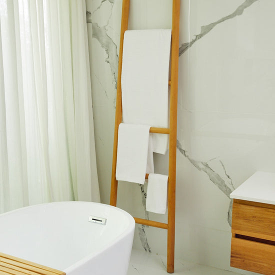 Toalla de baño blanca colgada en escalera de madera junto a bañera-blanco