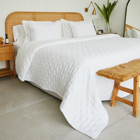 Cubrecama blanco liso sobre cama con cabecero de ratán natural-blanco