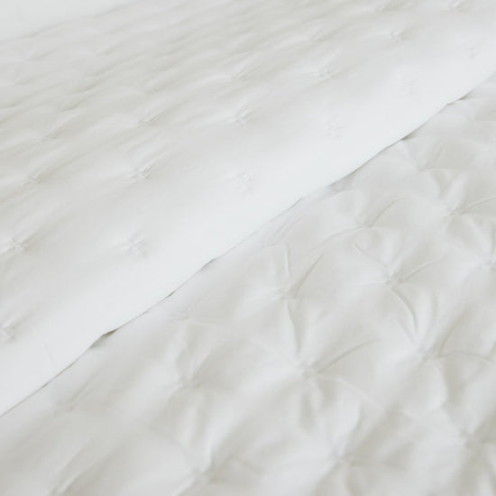 Cubrecama blanco con textura acolchada y patrón geométrico-blanco