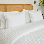 
                    
                      Cama con cubrecama blanco, almohadas y cabecero de ratán natural-blanco
                    
                  