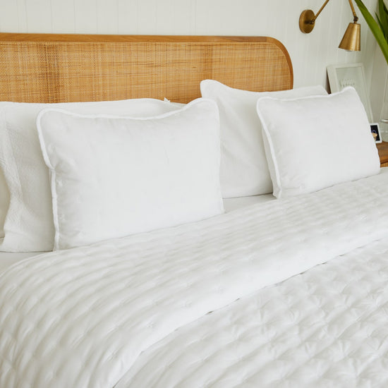 Cama con cubrecama blanco, almohadas y cabecero de ratán natural-blanco