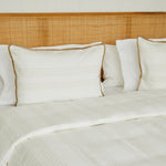 
                    
                      Cama con manta beige y almohadas blancas con ribete marrón-beige
                    
                  