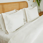 
                    
                      Cama con funda de edredón blanco, almohadas y cabecero de ratán-blanco
                    
                  