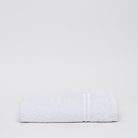 Toalla blanca de algodón con rayas texturizadas sobre fondo gris claro-blanco