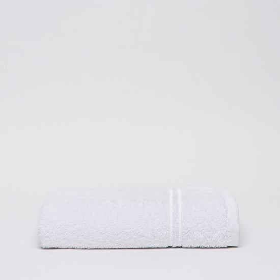 Toalla blanca de algodón con rayas texturizadas sobre fondo gris claro-blanco