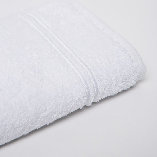 Toalla blanca enrollada mostrando textura suave y líneas decorativas-blanco