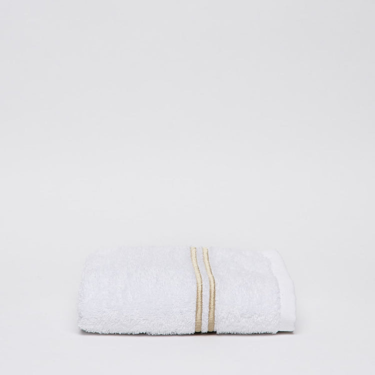 Toalla blanca enrollada con dos líneas decorativas beige-beige