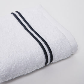 Toalla blanca enrollada con dos líneas negras decorativas-gris