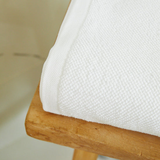 Toalla de baño blanca premium doblada sobre madera-blanco