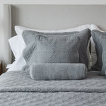 
                    
                      Almohadas decorativas grises y blancas sobre cama con cabecero tapizado-
                    
                  
