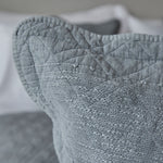 
                    
                      Detalle texturizado de funda almohada gris con costuras y tejido acolchado-
                    
                  