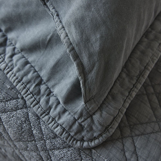 Detalle de funda almohada gris con costura y volante decorativo-