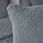 
                    
                      Detalle de funda de almohada gris con textura acolchada y costura lateral-
                    
                  