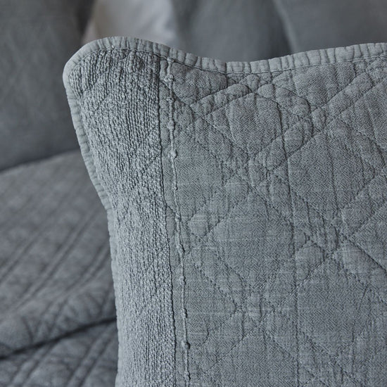 Detalle de funda de almohada gris con textura acolchada y costura lateral-