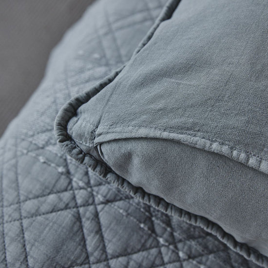Detalle de funda de almohada gris con costura y textura suave-