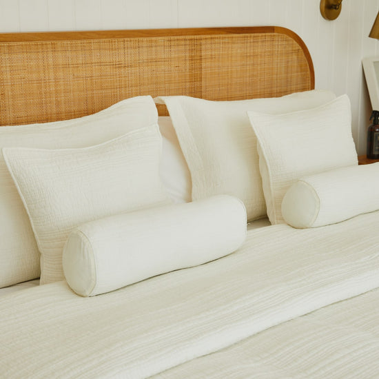 Cama con almohadas blancas y cabecero de ratán natural decorado-natural