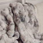 
                    
                      Manta suave gris y blanca con textura esponjosa acumulada en sofá-
                    
                  
