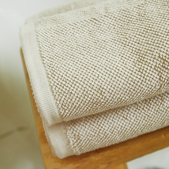 Toallas premium beige enrolladas mostrando textura tejida suave-beige