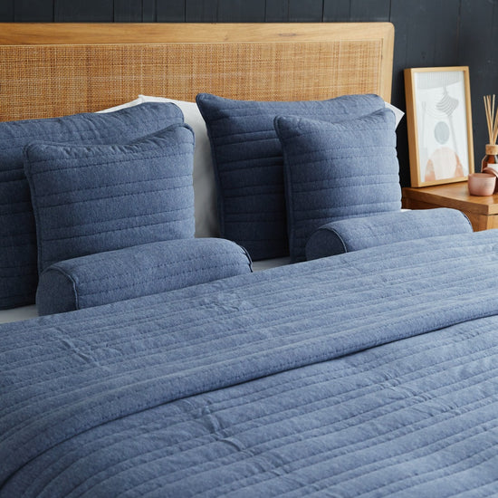 Cubrecama Pamplona azul con almohadas decorativas en cama con cabecero-azul
