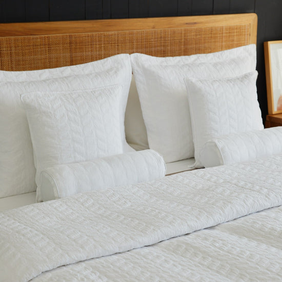 Almohadas blancas con funda acolchada sobre cama con cabecero de ratán-blanco
