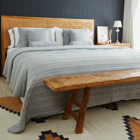 Cubrecama gris con patrón acolchado en cama de madera-gris