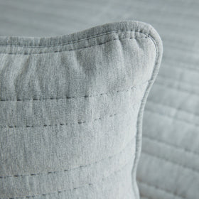 Detalle de funda de almohada gris con costuras decorativas visibles-gris