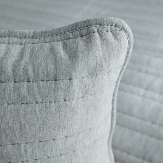 Detalle de funda de almohada gris con costuras decorativas visibles-gris
