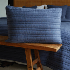 Funda almohada azul acolchada sobre banco madera junto sofá-azul