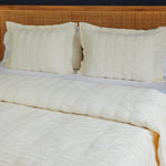 
                    
                      Cama con funda edredón natural, almohadas blancas y cabecero madera-natural
                    
                  