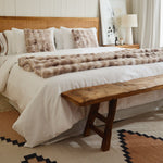 
                    
                      Manta de piel sintética beige sobre cama con almohadas decorativas-
                    
                  