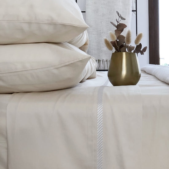 Cama con sábanas blancas de algodón egipcio y florero dorado-