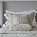 
                    
                      Almohadas decorativas beige y blancas sobre cama con cabecero gris-
                    
                  