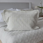 
                    
                      Funda de almohada acolchada color crema sobre cama con cabecero gris-
                    
                  