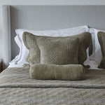 
                    
                      Almohada decorativa con funda verde oliva y ribete blanco en cama-
                    
                  