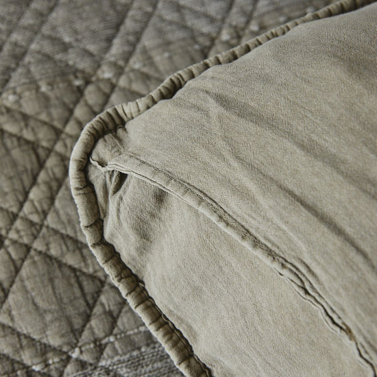 Funda almohada beige con elástico y textura acolchada detalle-