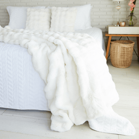 Manta blanca de piel sintética sobre cama con almohadas blancas-natural