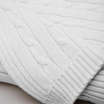 
                    
                      Manta tejida blanca para bebé con patrón de cables-
                    
                  