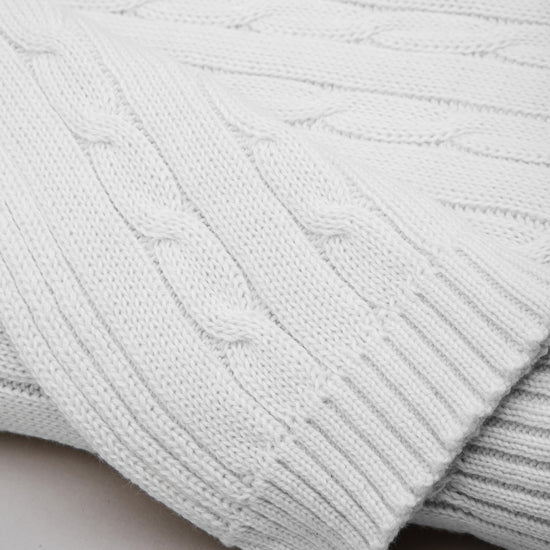 Manta tejida blanca para bebé con patrón de cables-