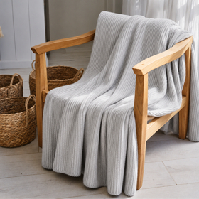 Manta tejida de angora color gris sobre superficie silla madera