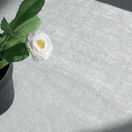Flor blanca con centro amarillo en jarrón sobre mantel gris-