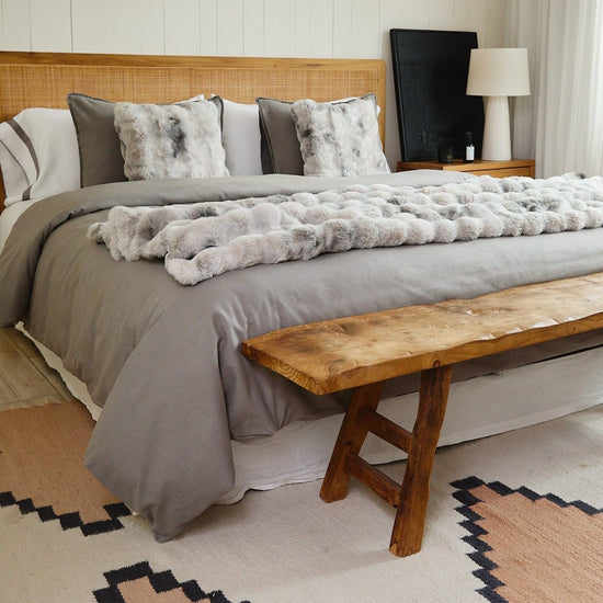 Cama con manta de piel sintética gris y almohadas decorativas-