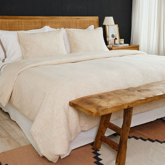 Cama con funda edredón beige claro y almohadas decorativas-