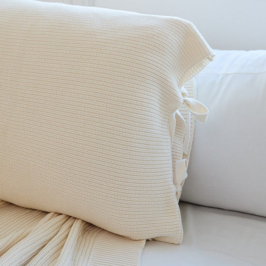 Funda de almohada beige tejida con lazos decorativos en blanco-