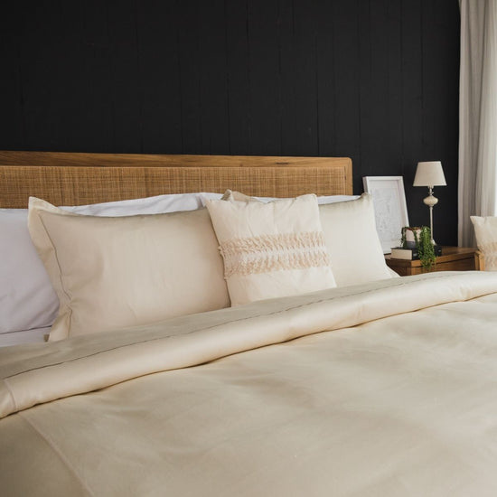 Cama elegante con funda edredón blanca y almohadas decorativas en tonos neutros-