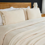
                    
                      Cama con funda de edredón beige y almohadas decorativas de textura acolchada-
                    
                  