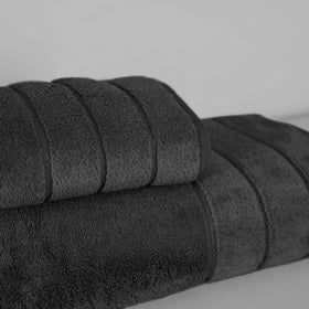 Set de toallas negras enrolladas y apiladas sobre fondo gris-negro