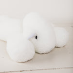 
                    
                      Peluche blanco suave en forma de conejo acostado sobre superficie clara-blanco
                    
                  