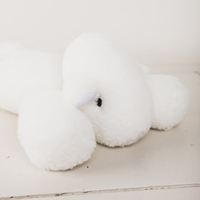 Peluche blanco suave en forma de conejo acostado sobre superficie clara-blanco